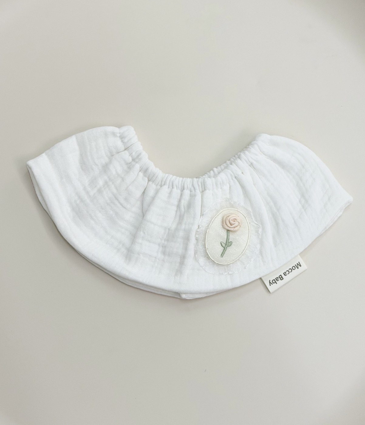 Babero con volante y rosa · marfil